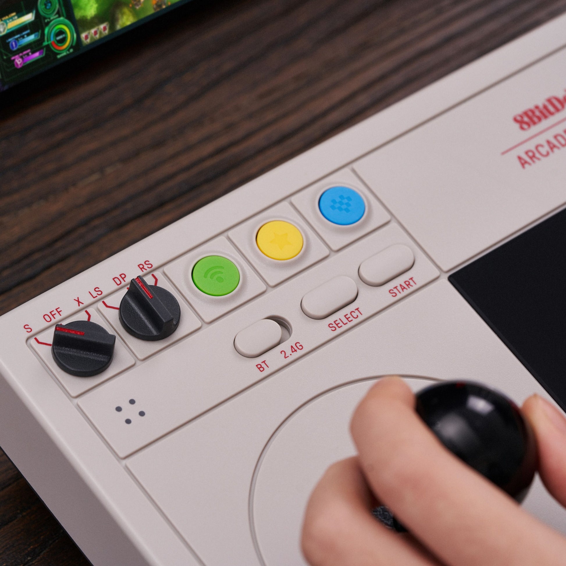 8Bitdo Arkade joystick hvid trådløs controller med farvede knapper, til runde kontakter og arkadestik, skærm i baggrunden.