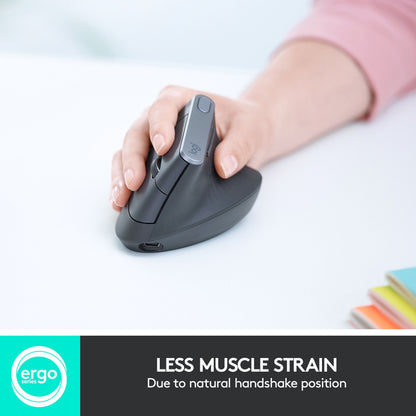 Logitech MX Vertikal trådløs mus, sort, hånd i brug ved notesbøger, tekst: MINDRE MUSKELBELASTNING.
