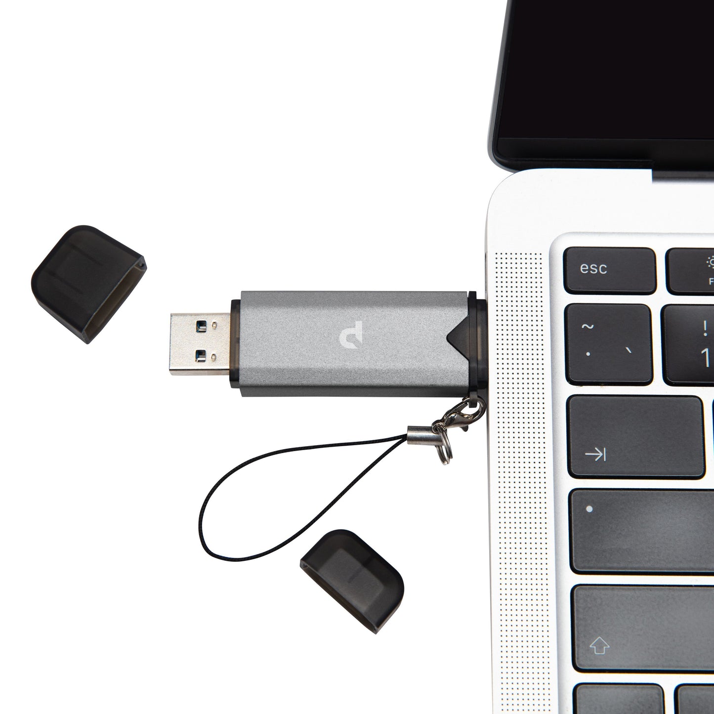 Plexgear Hukommelseskortlæser til SD og Micro-SD sølv med sort hætte og strop, tilsluttet laptop USB-port, løse hætter ved siden af.
