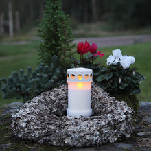 Star Trading gravlys med LED, blid flamme, placeret i hjerteformet krans af grangrene og rød-hvide alpevioler på natursten.