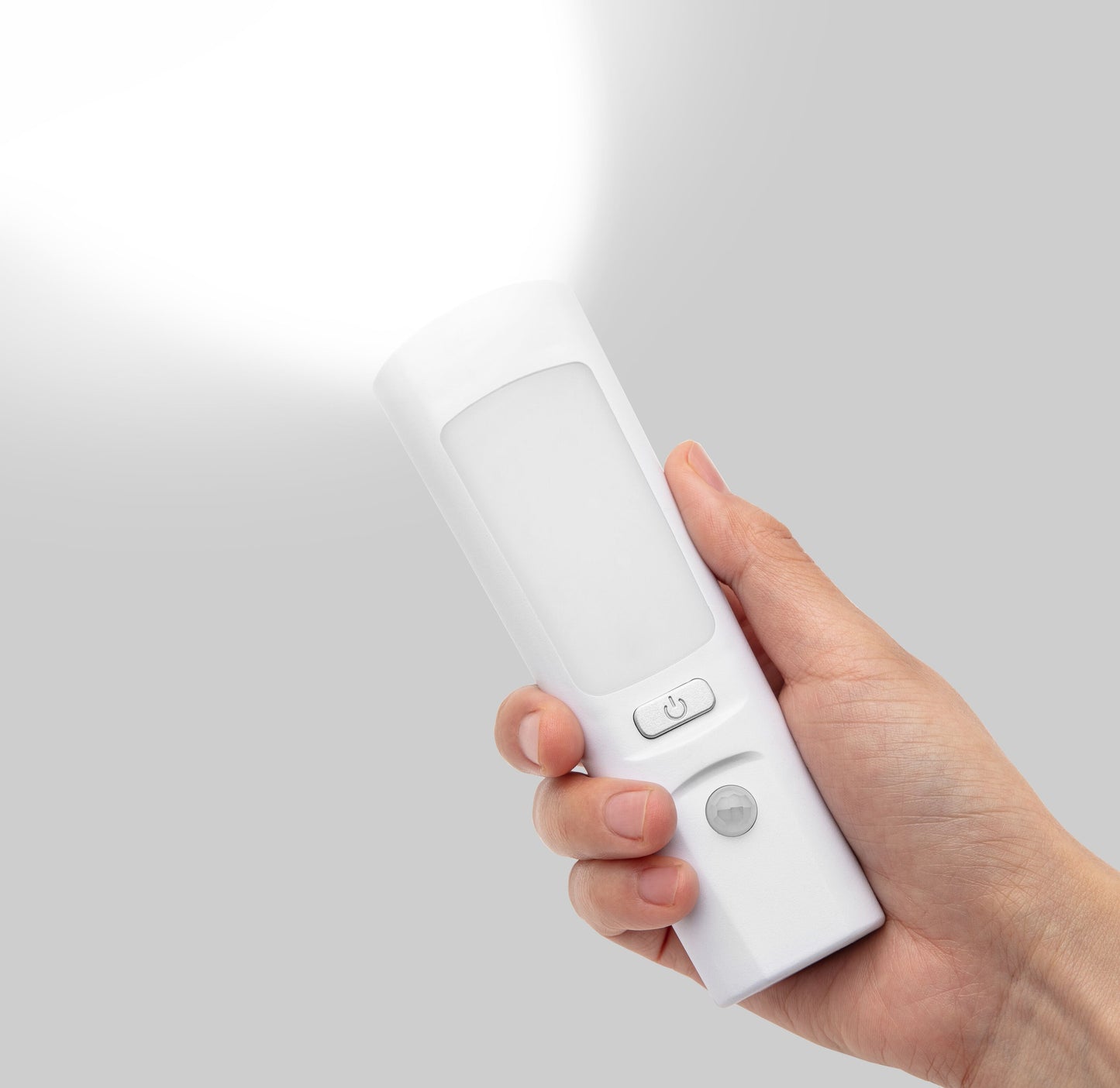 Luxorparts Genopladelig lommelygte og natlampe tændt i hånd, udsender kraftigt lys mod grå baggrund.
