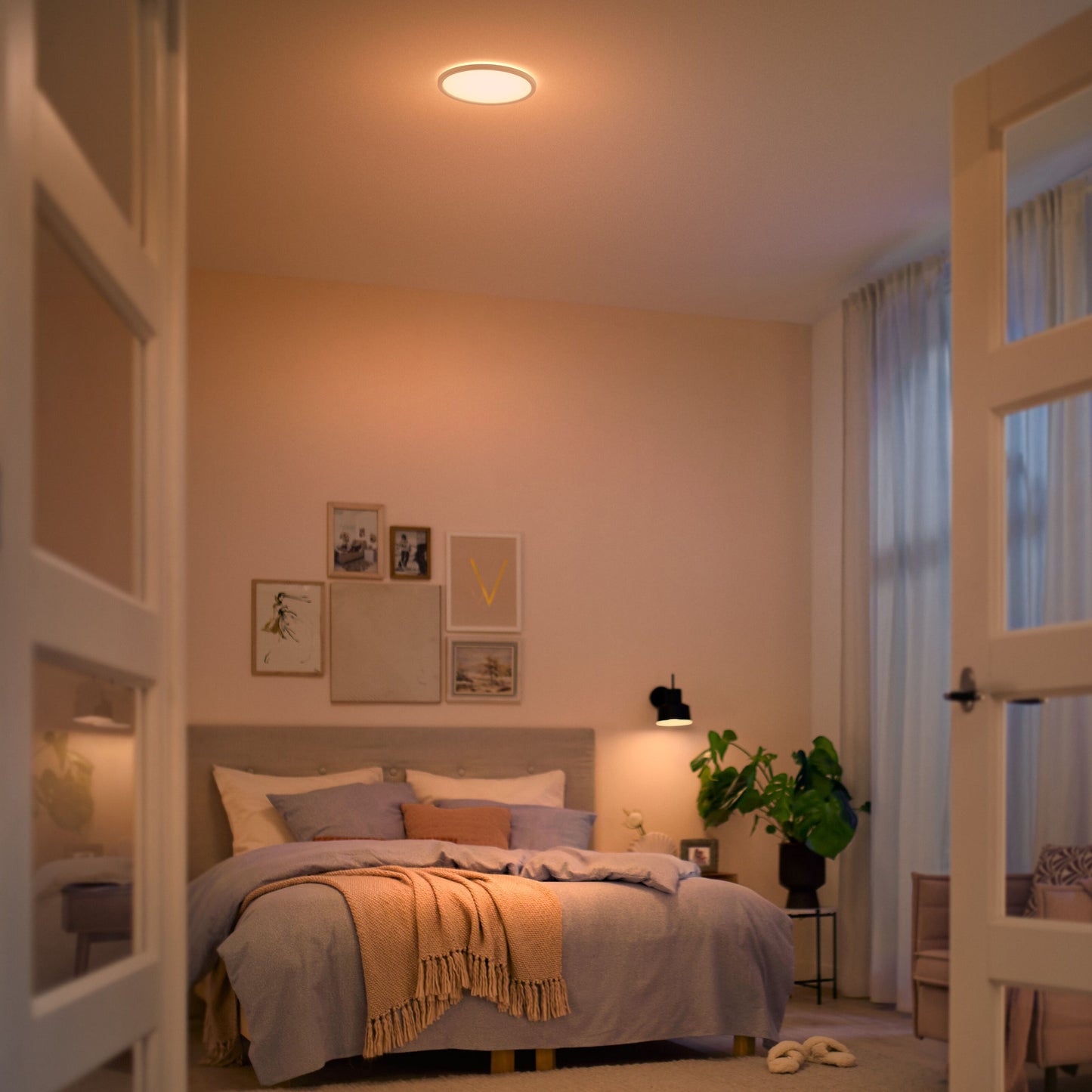 Philips Mauve Sceneswitch LED loftlampe 1500 lm varm hvid, loftmonteret over seng med beige og orange sengetøj.