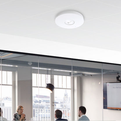 TP-Link Omada EAP610 WiFi 6 AX1800 access point, loftmonteret i kontormødelokale med folk under og store vinduer synlige.