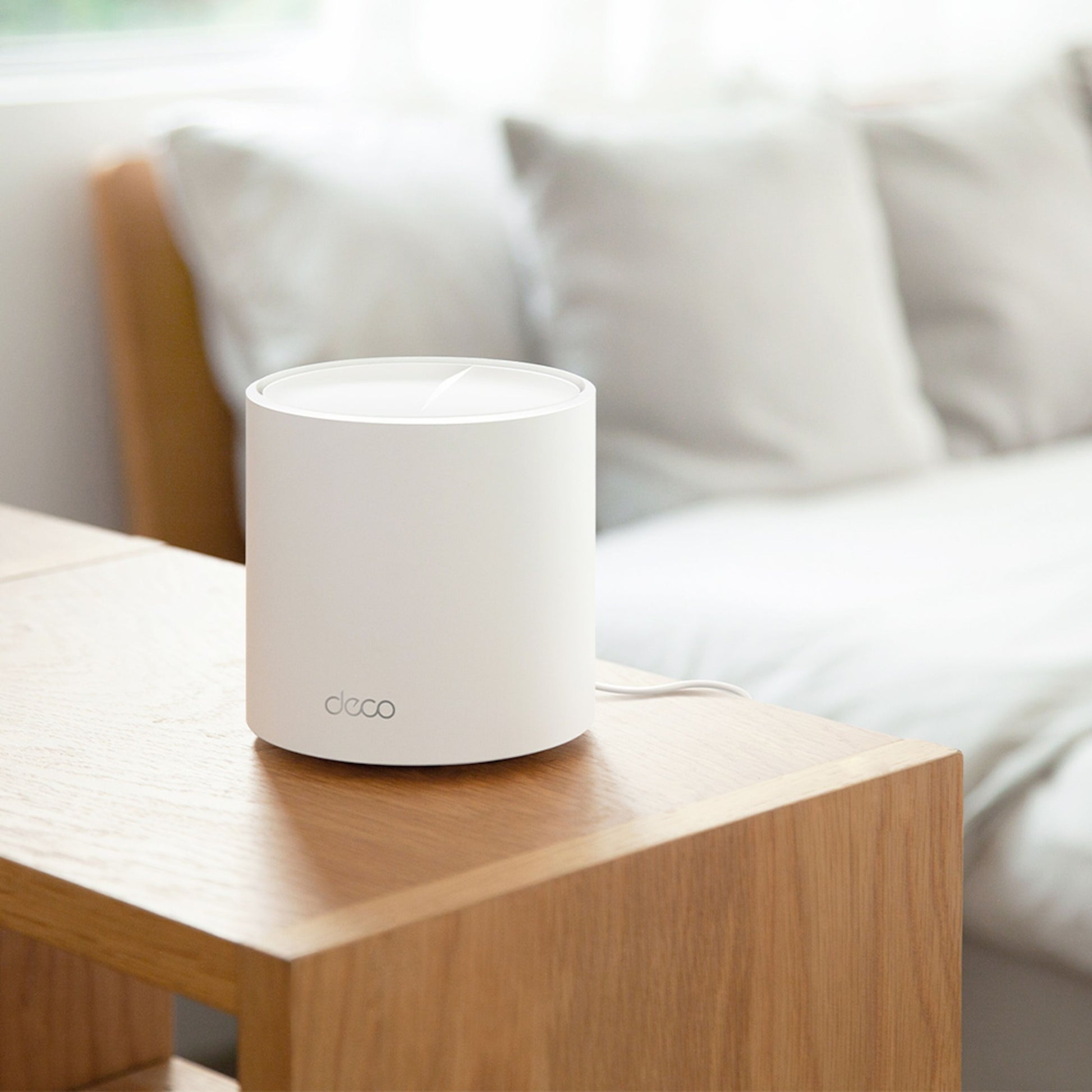 TP-Link Deco X50 AX3000 3-pakke mesh router på træbord ved lys sofa med puder i moderne stue.