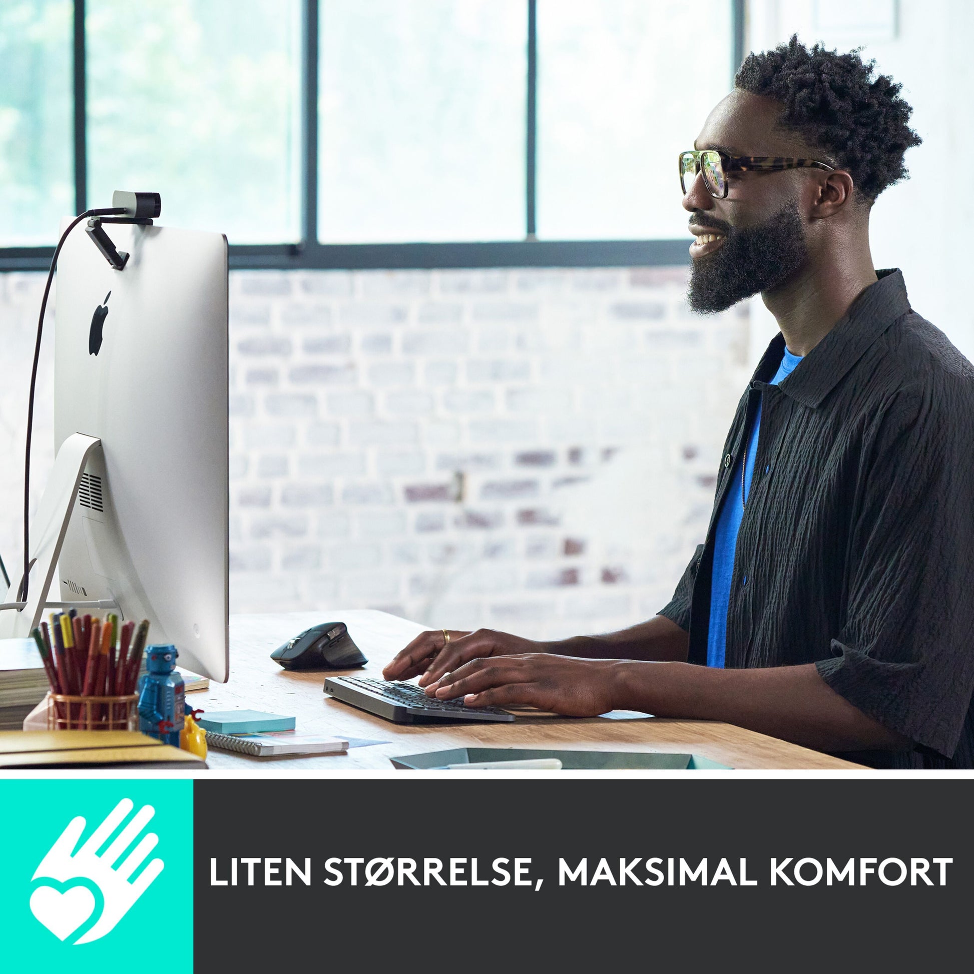 Logitech MX Keys Mini Trådløst tastatur grå på skrivebord, norsk tekst "Liten størrelse, maksimal komfort" vises.