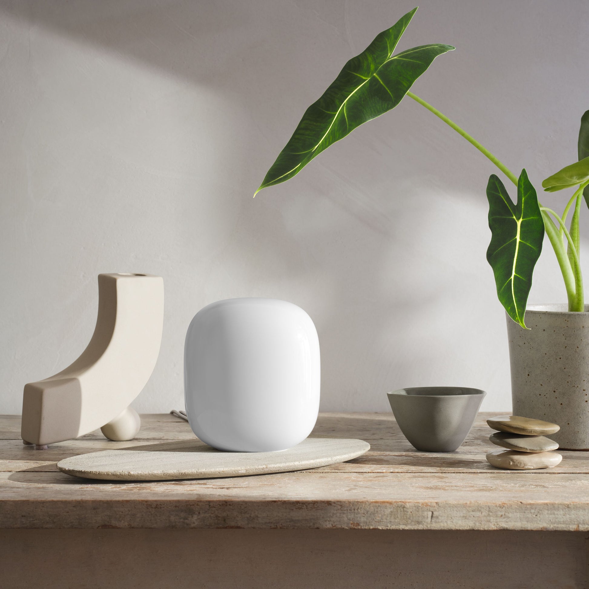 Google Nest Wifi Pro AXE4200 1-pakke, hvid WiFi 6E router på træbord med keramikskåle og grøn plante.