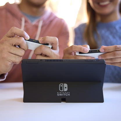 Nintendo Switch OLED spillekonsol 7" rød/blå, vises brugt med controllere og opstillet konsol.