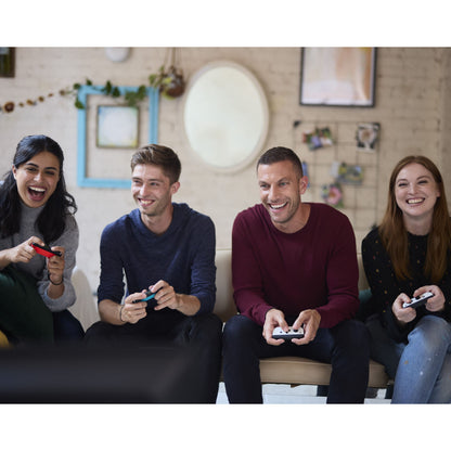 Nintendo Switch (OLED) spillekonsol 7" rød/blå bruges til multiplayer gaming, synlig i brug af unge voksne i stueinteriør.