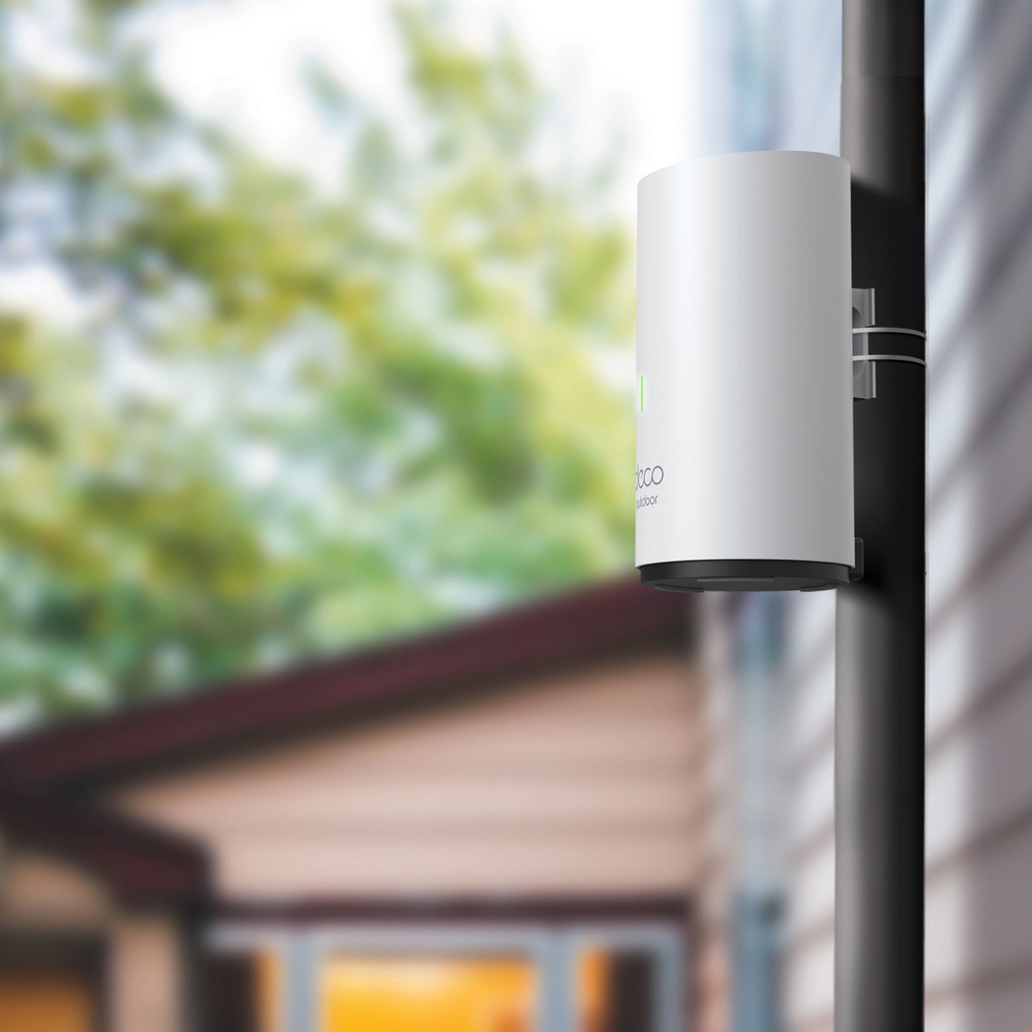 TP-Link Deco X50-Outdoor PoE AX3000 Mesh hvid, monteret på sort stolpe udenfor beige bygning, Wi-Fi 6 access point.