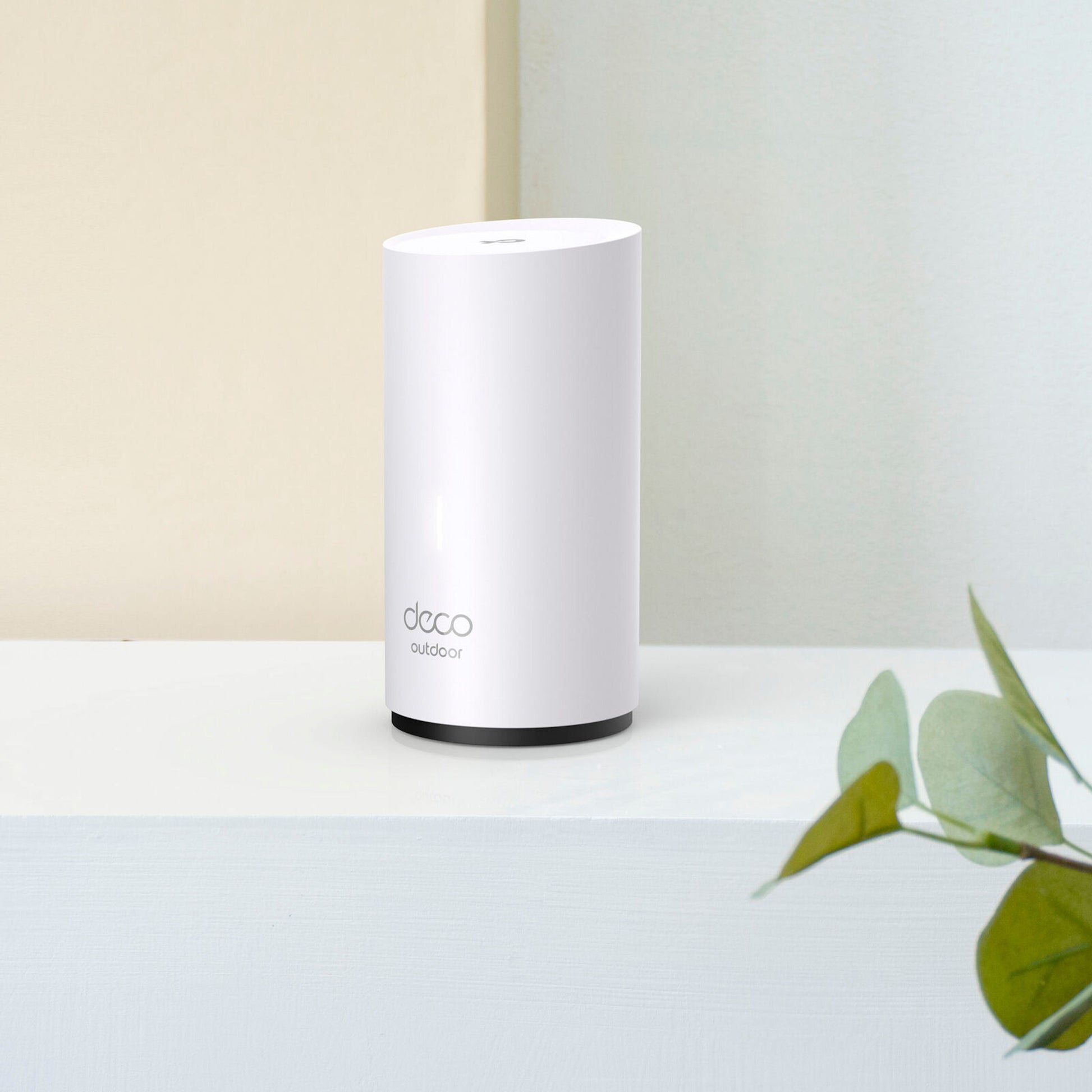 TP-Link Deco X50-Outdoor AX3000 Mesh WiFi 6, hvid, synlig PoE-port, placeret ved grøn plante.