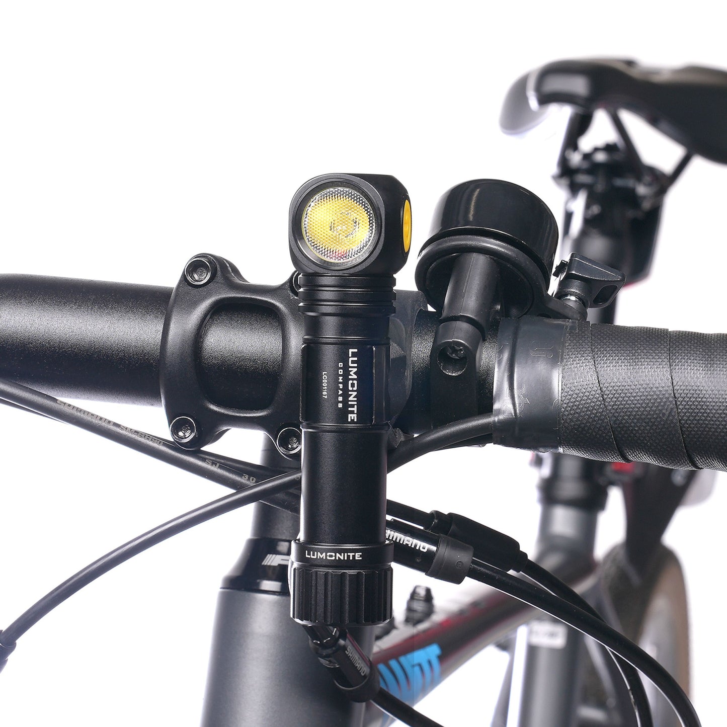 Lumonite Kompas pandelampe 1250 lm, IP69, monteret på sort cykelstyr ved siden af ringeklokke.