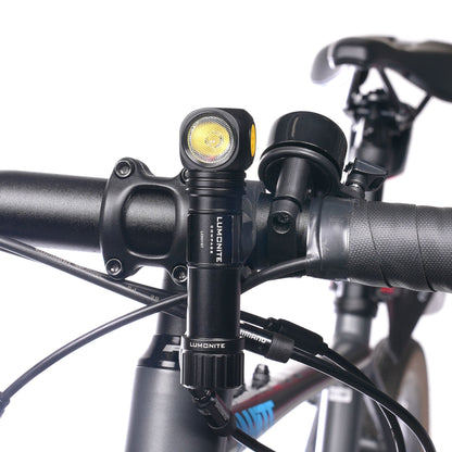 Lumonite Kompas pandelampe 1250 lm, IP69, monteret på sort cykelstyr ved siden af ringeklokke.