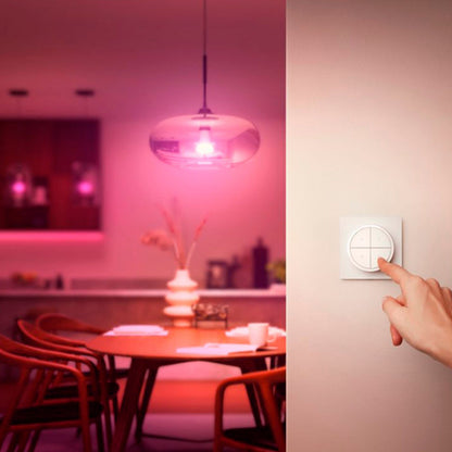Hånd bruger Philips Hue Tryk på Drejeknap Fjernbetjening Hvid til at styre pink lys over spisebord med stole.