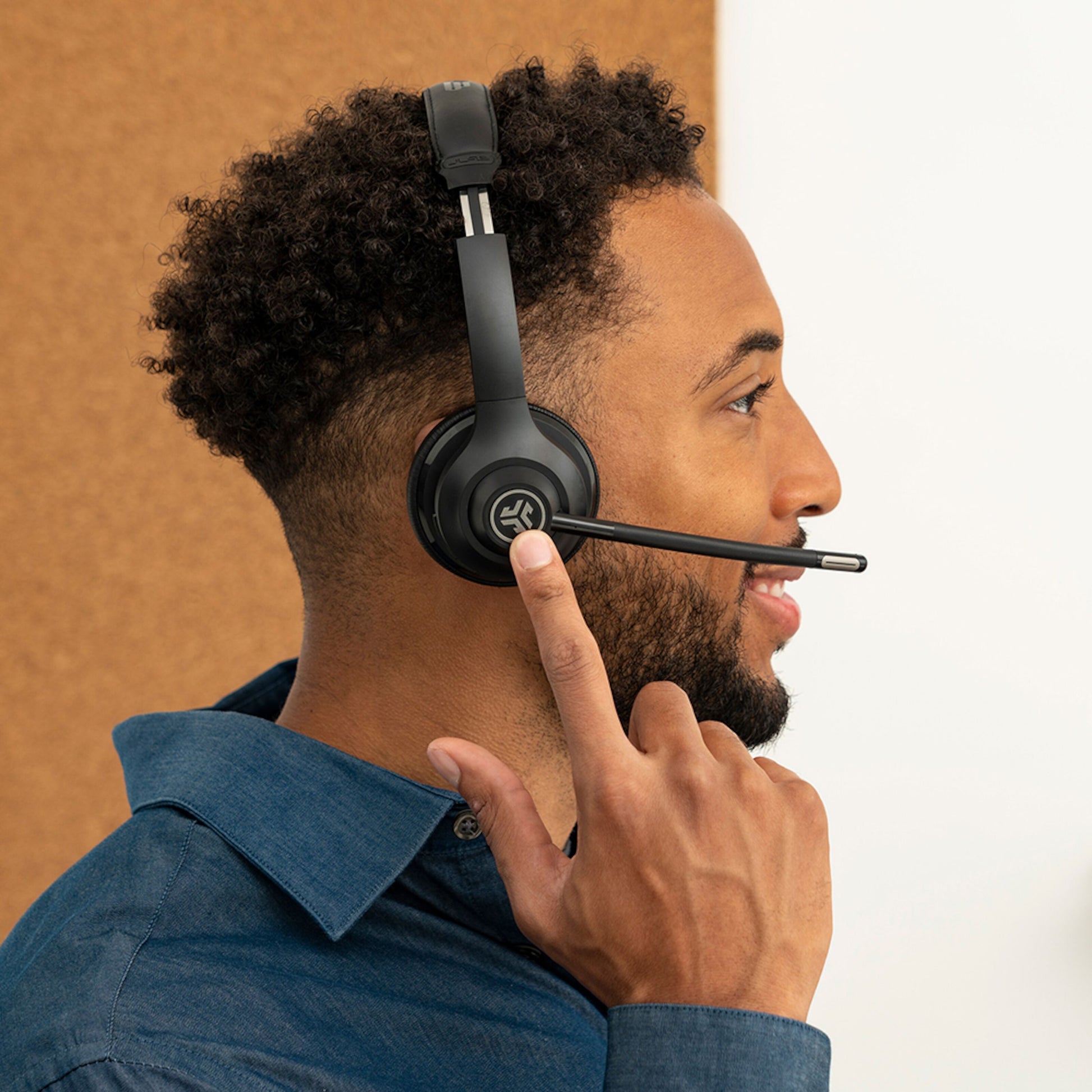 JLab GO Arbejde Trådløst headset, blå, vises på hoved, 45 timers batteritid, brun og hvid baggrund.