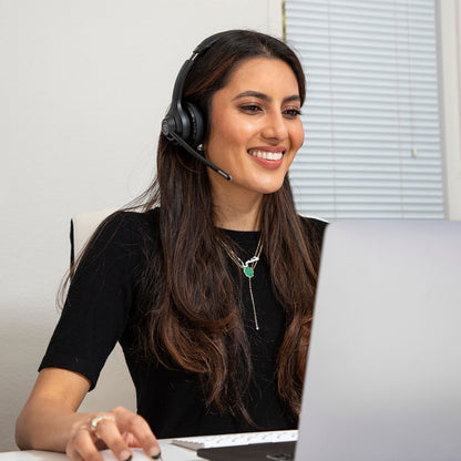 JLab GO Arbejde Trådløst headset sorterer bæres af kvinde foran laptop, synlig mikrofon og ørekopper, multipoint parring.