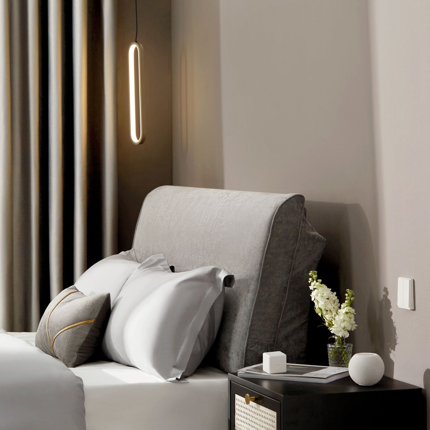 Aqara Cube T1 Pro smart home controller ved seng, grå sengegavl, monokrom puder, rund smart højttaler.