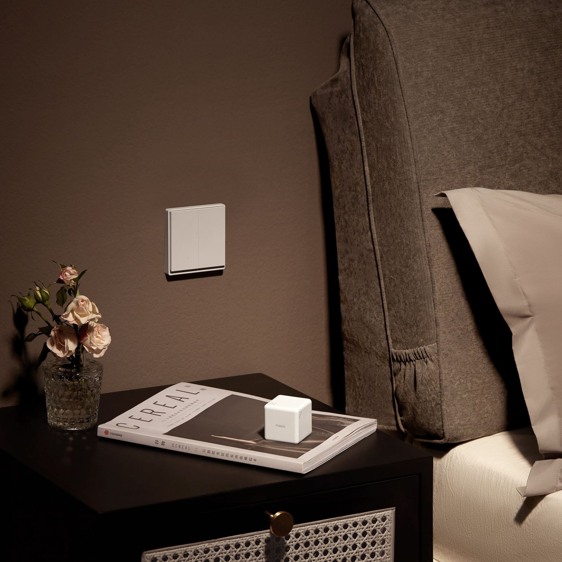 Aqara Cube T1 Pro smart device på natbord med glasvase, pink blomster, bog TREE TALK, seng med brun gavl og beige sengetøj.