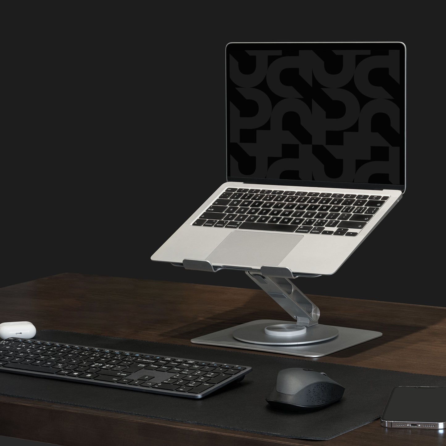 Bærbar på sort Plexgear Foldbart laptopstativ på mørkt træbord med trådløst tastatur, mus, musemåtte og smartphone.