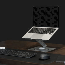 Bærbar på sort Plexgear Foldbart laptopstativ på mørkt træbord med trådløst tastatur, mus, musemåtte og smartphone.