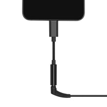 Smartphone tilsluttet USB-C til 3,5 mm sort adapter, kabel peger nedad og bøjer til højre i 90 graders vinkel.