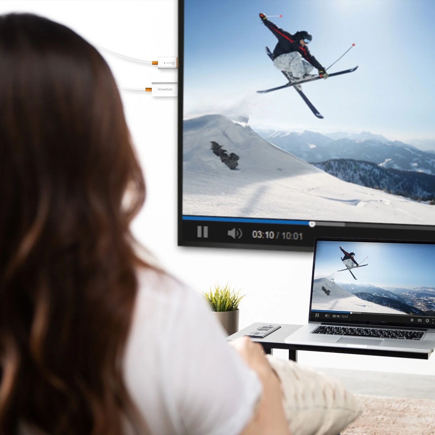 J5create SkærmCast trådløs adapter spejler ski-video på vægskærm og laptop, sorterer enhed synlig ved computer.