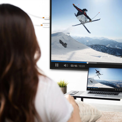 J5create SkærmCast trådløs adapter spejler ski-video på vægskærm og laptop, sorterer enhed synlig ved computer.