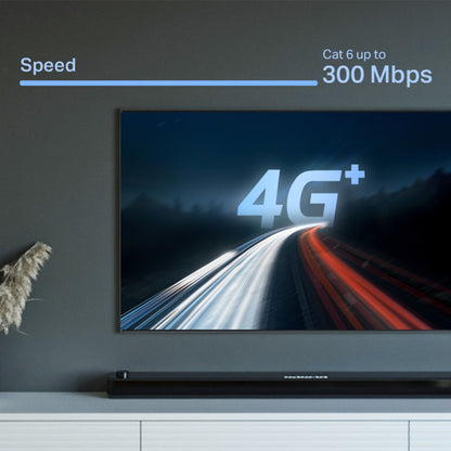 TP-Link X10-4G 4G+-router med modem AX1500 Speed Cat 6 op til 300 Mbps vises på tv-skærm, grå væg i baggrunden.