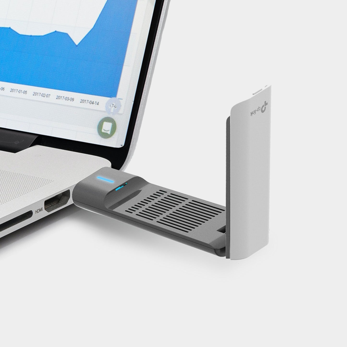 Tp-Link Archer TX20UH AX1800 trådløst USB-netværkskort tilsluttet sølv laptop, ventileret design, blå/hvid graf på skærm.