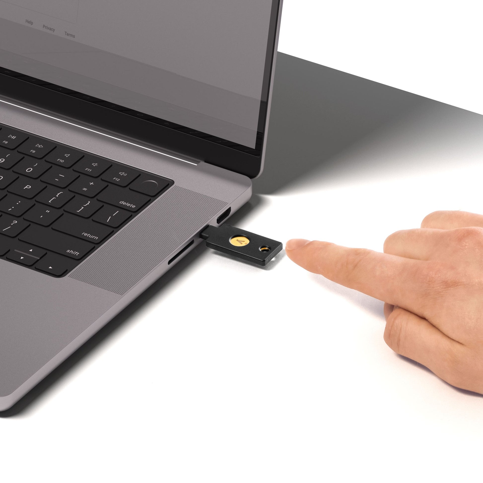Yubico Sikkerhedsnøgle NFC med USB-C tilsluttet laptop USB-port, hånd nærmer sig sikkerhedsnøglen.
