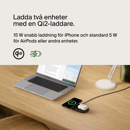 Belkin BoostCharge Pro 2-i-1 Qi2 15 W oplader til iPhone og AirPods på skrivebord ved siden af åben bærbar og lampe.