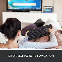 Logitech K400 Plus trådløst tastatur med touchpad i brug foran tv, sort model, synlig tastaturoverflade.