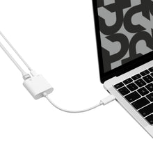 Gigabit-netværkskort med PD-opladning USB-C tilsluttet sølvfarvet laptop, til kabler forbundet, skærm med abstrakt mønster.
