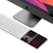 Apple iMac Pro med sølv Magic Keyboard og trådløst numerisk tastatur i Space Grey, macOS-tapet på skærmen.