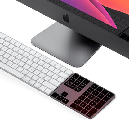 Apple iMac Pro med sølv Magic Keyboard og trådløst numerisk tastatur i Space Grey, macOS-tapet på skærmen.
