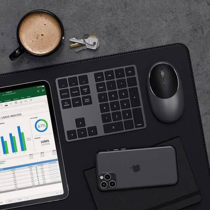Satechi Trådløs numerisk tastatur Space Grey ved siden af iPad med grafer, sort iPhone og trådløs mus.