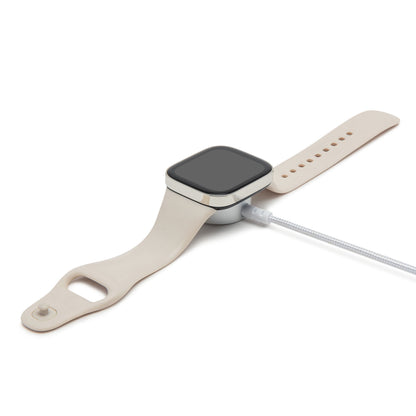 Beige firkantet smartwatch oplades på rund Apple Watch opladerkabel med USB-C 1,2 m flettet kabel.