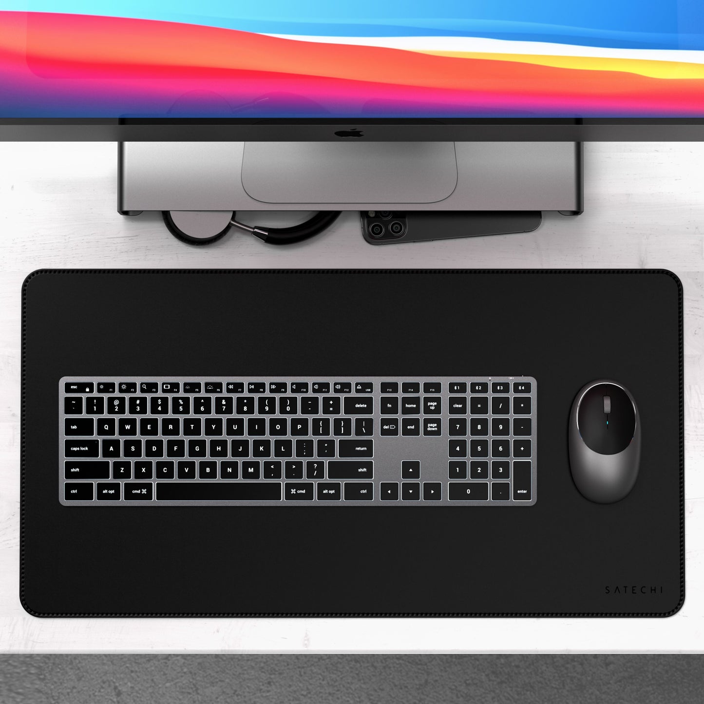 Apple iMac, Satechi X3 trådløst tastatur med numerisk tastatur, mus og sort Satechi skrivebordsmåtte, kabler og telefon.