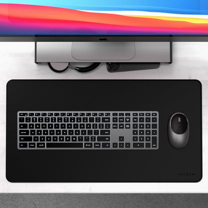 Apple iMac, Satechi X3 trådløst tastatur med numerisk tastatur, mus og sort Satechi skrivebordsmåtte, kabler og telefon.