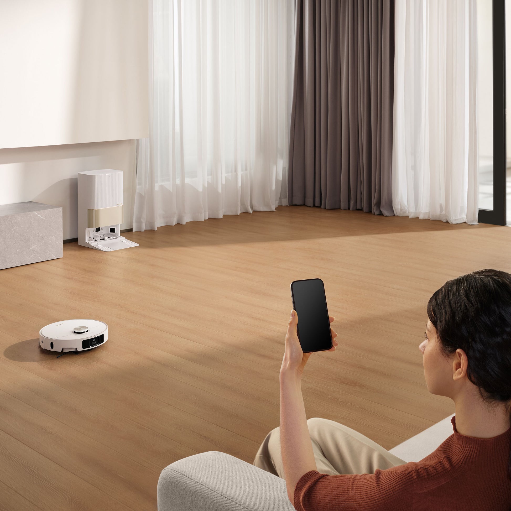 Dreame X40 Ultra fuldautomatisk støvsugerrobot styres via smartphone, ses i lyse rum med trægulv og hvide gardiner.