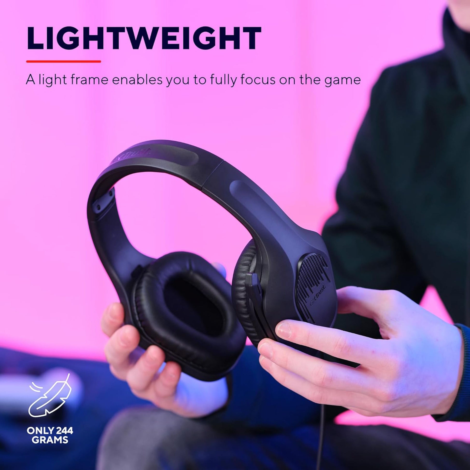 Trust GXT415 Zirox sort over-ear gaming headset, 244g, vises i hånd mod pink baggrund.