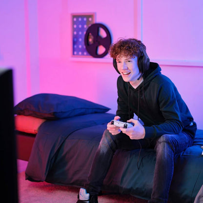 Trust GXT415 Zirox Gaming-headset sort bæres af ung person, sorte krøller, synlig mikrofon, pink/lilla belysning.