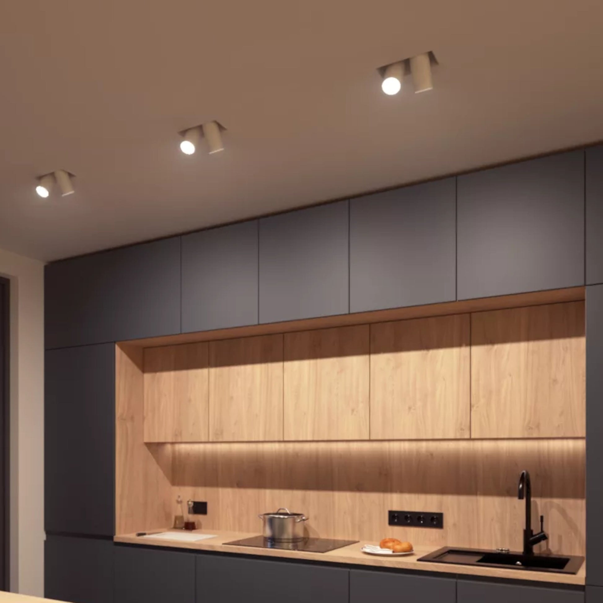 Philips Hue White Ambiance MR16 400 lm installeret i køkken med mørke skabe, lys træ-bagvæg og sort armatur.