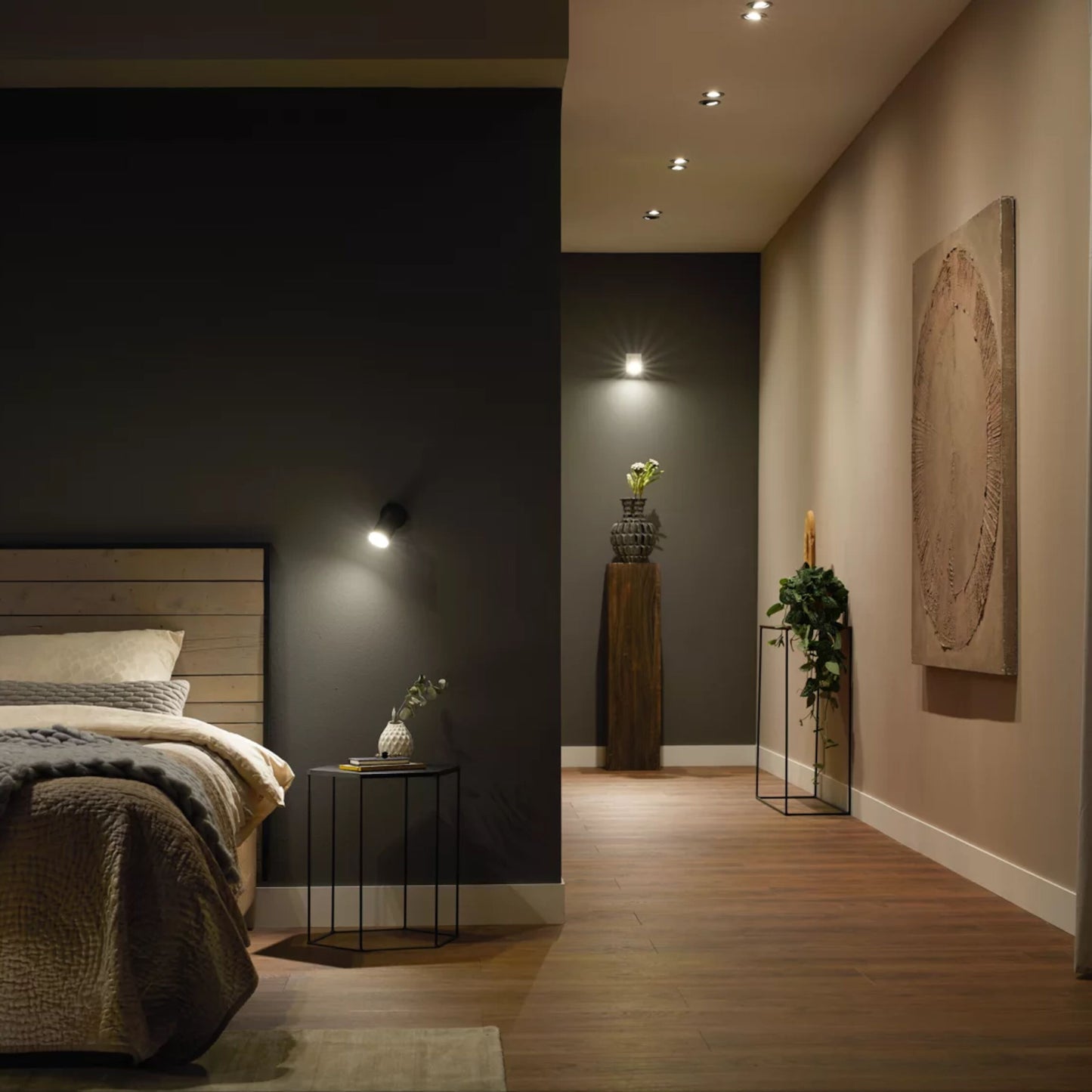 Hue White Ambiance MR16 400 lm spotlights smart belysning, seng, natbord, trægulv, planter ved mørk væg.
