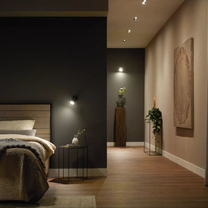 Hue White Ambiance MR16 400 lm spotlights smart belysning, seng, natbord, trægulv, planter ved mørk væg.