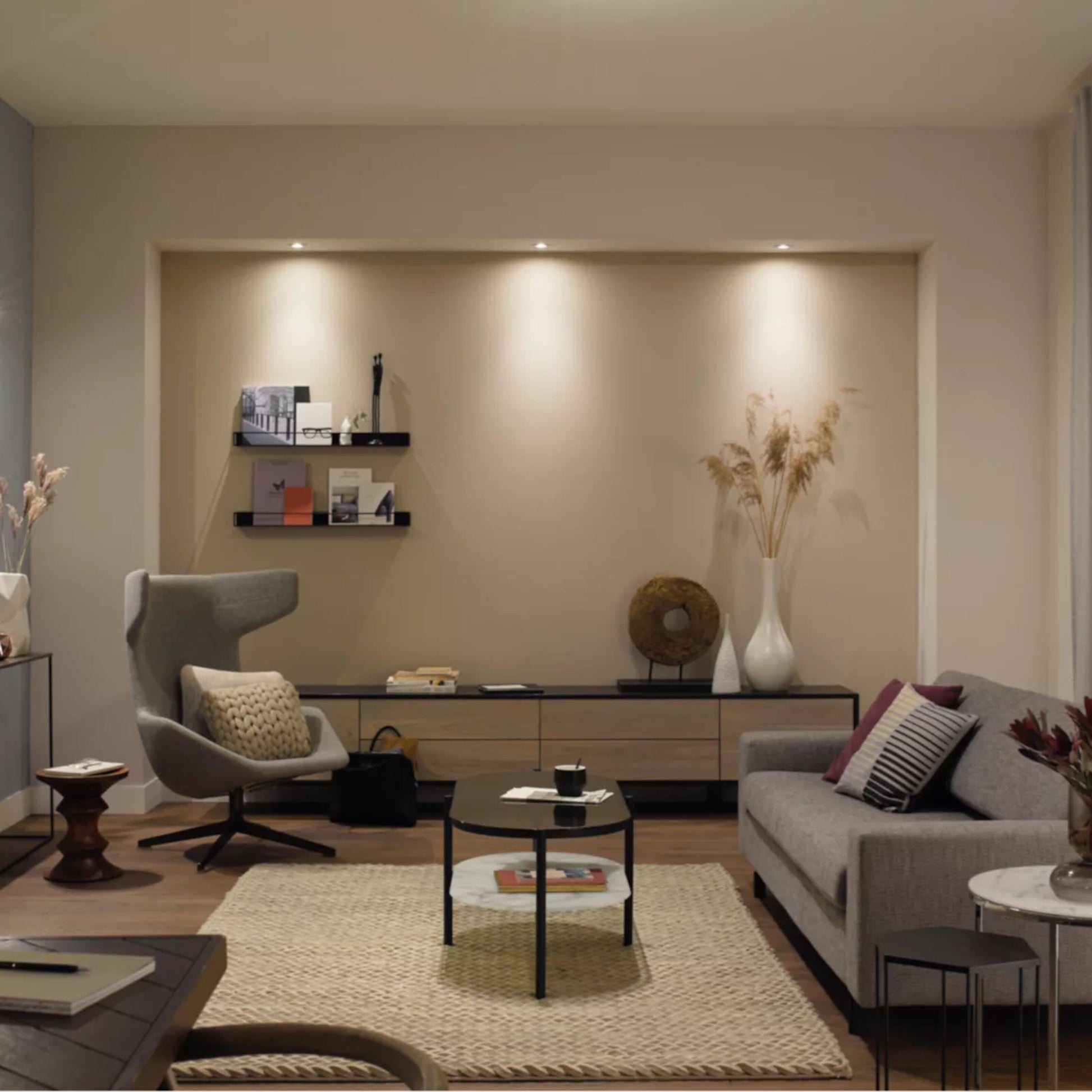 Philips Hue White Ambiance MR16 400 lm LED-spot synlig i stue med grå sofa, rundt sofabord og beige gulvtæppe.
