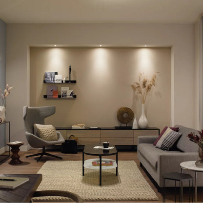 Philips Hue White Ambiance MR16 400 lm LED-spot synlig i stue med grå sofa, rundt sofabord og beige gulvtæppe.