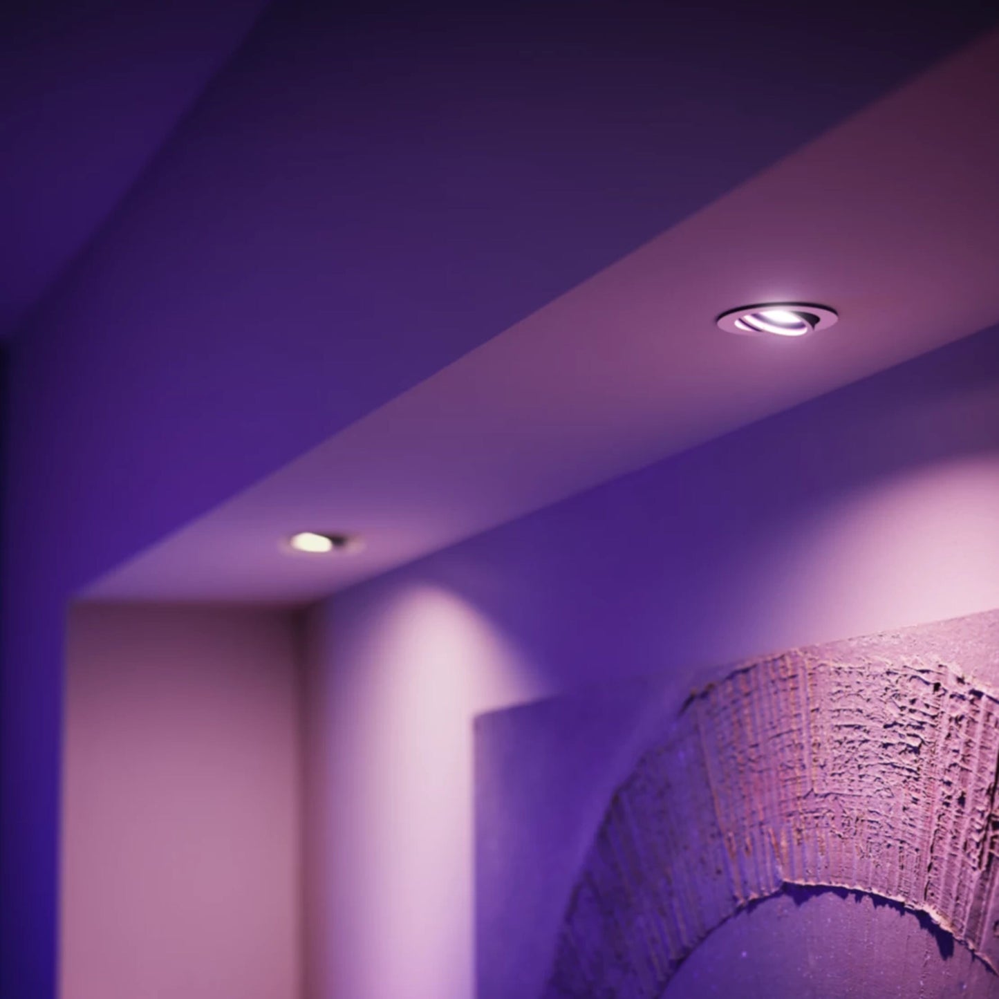 Philips Hue Hvid og Farveambiance MR16 400 lm lyser i lilla, to runde loftlamper, tekstureret skulptur til højre.