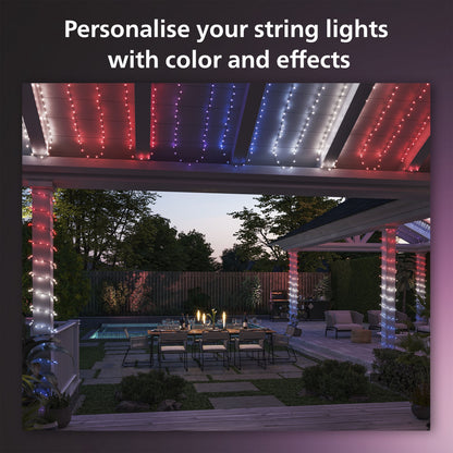 Philips Hue Festlig lyskæde 250 LED, rød/hvid/blå, monteret udendørs over terrasse og pool.