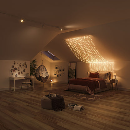 Philips Hue Festlig lyskæde 250 LED over seng, synlig hængestol, skrivebord med fotos, puf, bøger på trægulv.