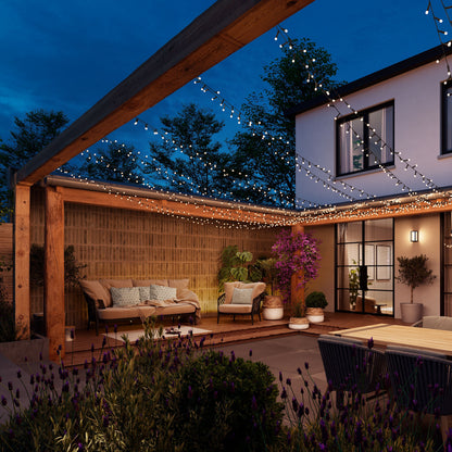 Philips Hue Festlig lyskæde 250 LED farvegradient monteret under træpergola udendørs ved moderne hus.